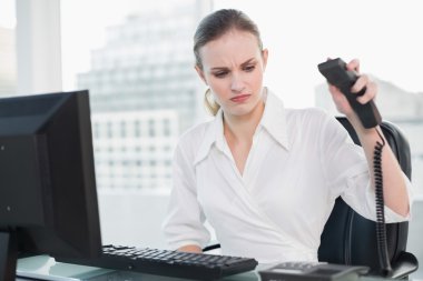 zły kobieta siedzi przy biurku wieszania telefon