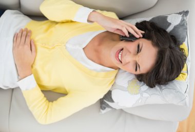 Casual esmer telefonla sarı hırka içinde gülüyor