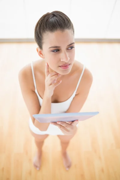 Thoughtful woman in white sportswear holding a tablet pc — Stock Photo, Image