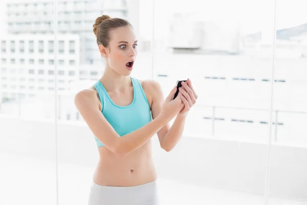 Sportieve verrast vrouw bedrijf smartphone — Stockfoto