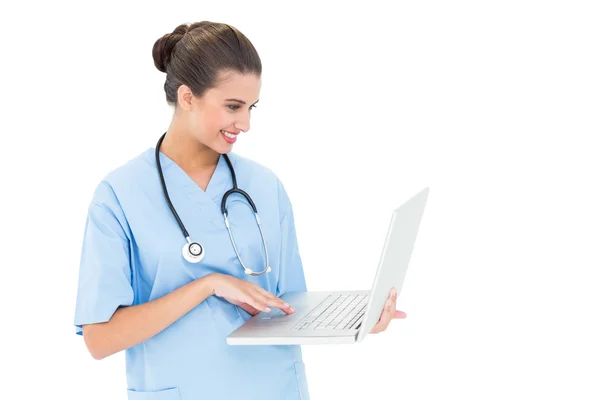 快乐护士在使用一台笔记本电脑的蓝色磨砂 — 图库照片