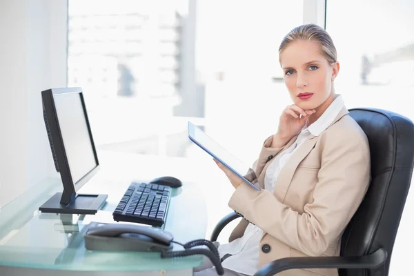 Thoughtful blonde businesswoman using tablet — Stock Photo, Image