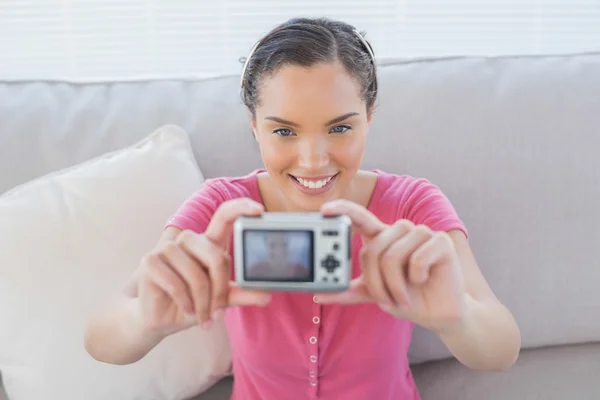 Happy woman sitting on her sofa taking a picture of herself — Stock Photo, Image