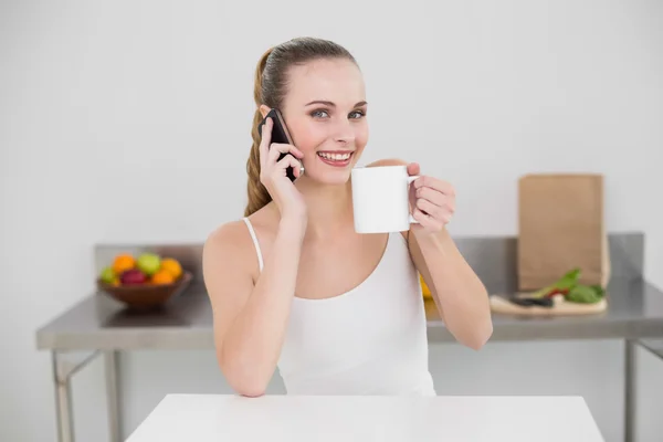 Happy young woman making a phone call and holding a mug — Stock Photo, Image