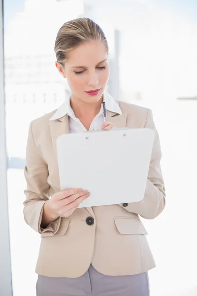 Focalisé blonde femme d'affaires tenant presse-papiers — Photo