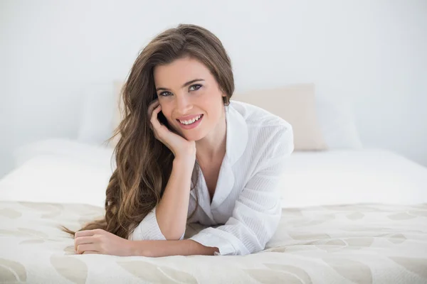 Mujer sonriente en pijama blanco acostada en su cama —  Fotos de Stock