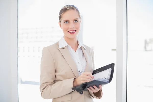 Sonriente rubia mujer de negocios sosteniendo datebook de pie — Foto de Stock