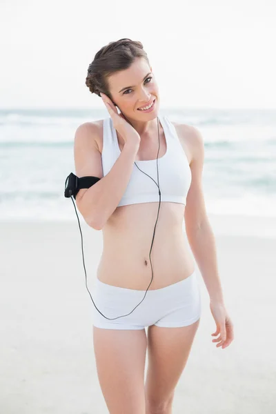 Blij slank model in witte sportkleding luisteren naar muziek — Stockfoto