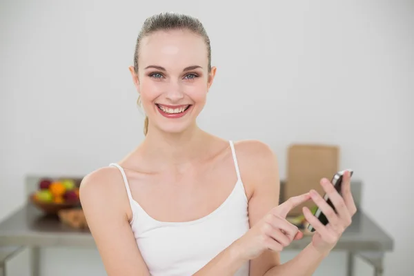 Glückliche junge Frau hält Smartphone lächelnd in die Kamera — Stockfoto