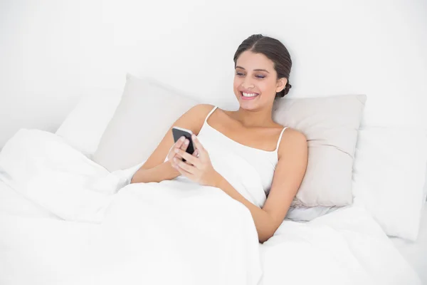 Modell i vit pyjamas textilen med en mobiltelefon — Stockfoto