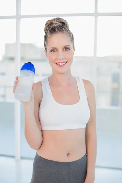 Smiling sporty blonde holding flask — Stock Photo, Image