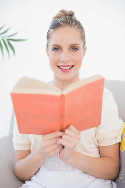 Smiling fresh model reading book sitting on sofa — Stock Photo, Image