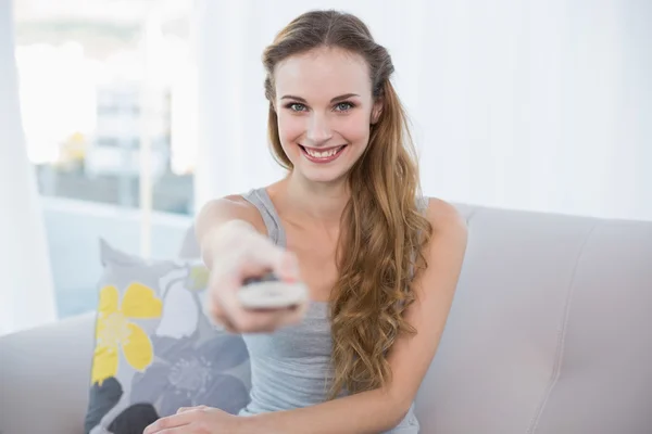 Happy young woman sitting on sofa watching tv — Stock Photo, Image