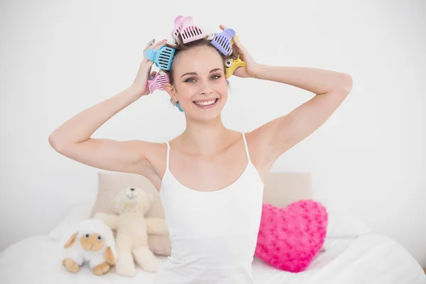 Pleased woman fixing her hair curlers — Stock Photo, Image