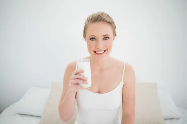 Natural smiling blonde holding glass of milk — Stock Photo, Image