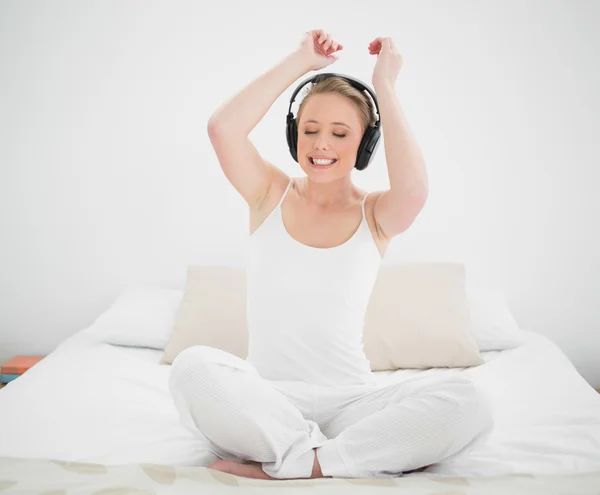 Natürliche fröhliche Blondine hört Musik und Arme in der Luft — Stockfoto