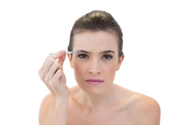 Concentrated model plucking her eyebrows — Stock Photo, Image