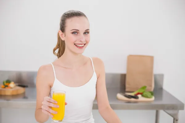 Cheerful young woman holding glass of orange juice — Stock Photo, Image
