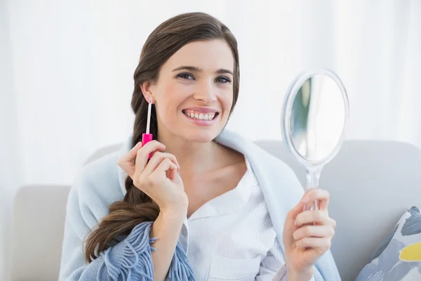 Happy woman in white pajamas applying gloss — Stock Photo, Image