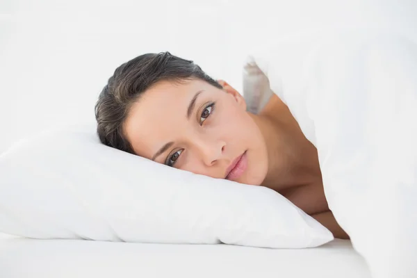 Klidnou neformální brunetka ležící v posteli — Stock fotografie