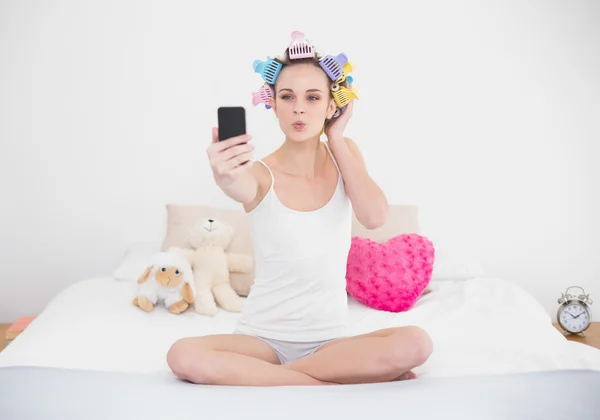 Mulher em encrespadores de cabelo tirando uma foto de si mesma com telefone celular — Fotografia de Stock