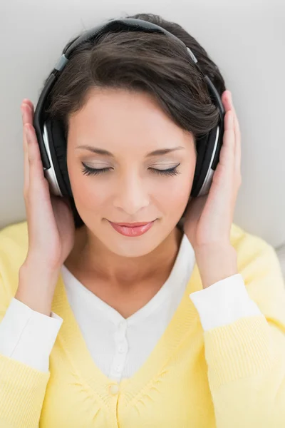 Calm casual brunette in yellow cardigan enjoying music — Stock Photo, Image
