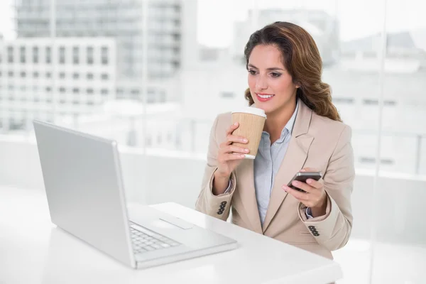 Businesswoman holding disposable cup and smartphone