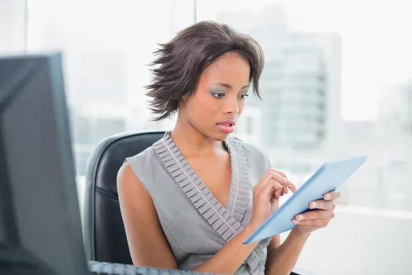 Хмурая деловая женщина сидит за столом, держа планшет ПК — стоковое фото