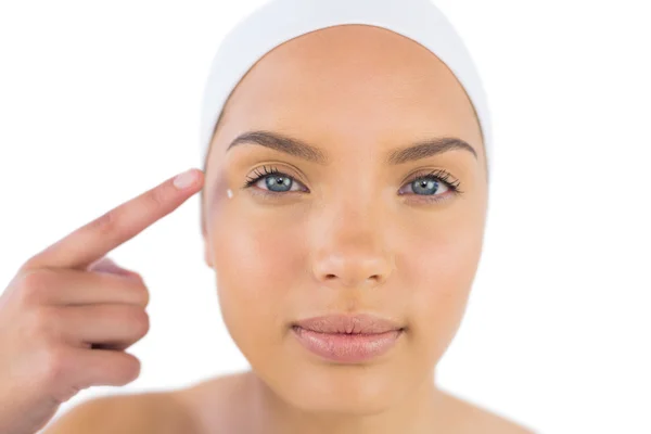 Pretty woman wearing headband putting cream on her face — Stock Photo, Image