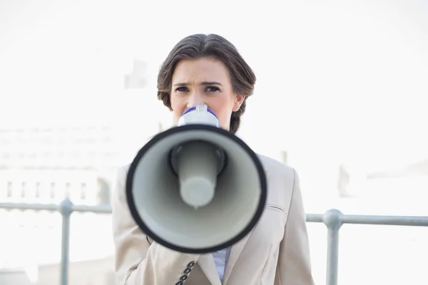 Frowning stylish businesswoman using a megaphone — Stock Photo, Image