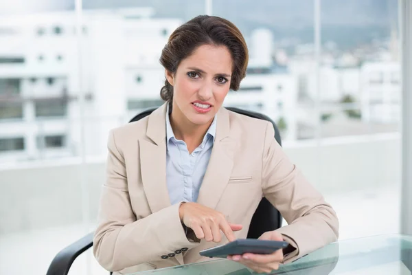 Annoyed businesswoman using calculator — Stock Photo, Image