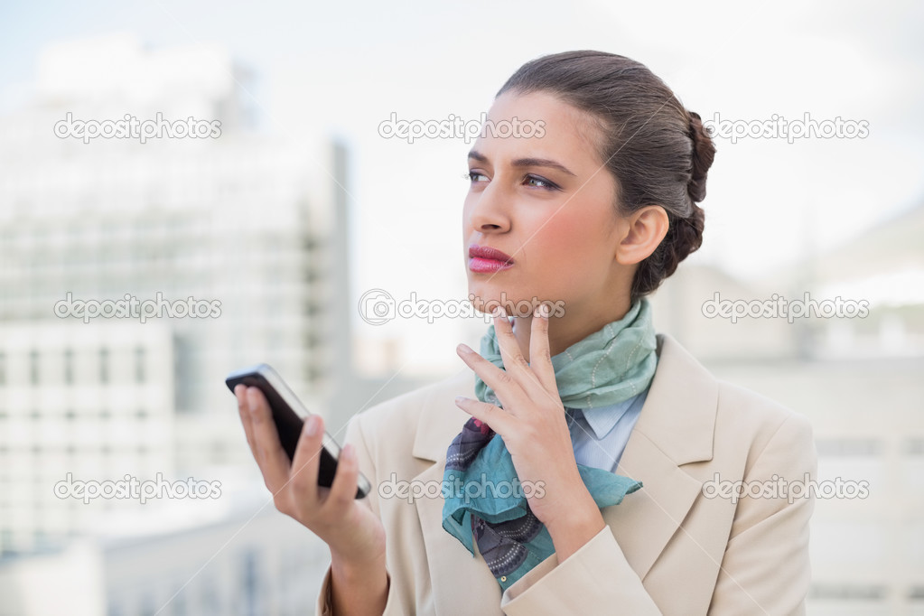 Thoughtful businesswoman holding a mobile phone