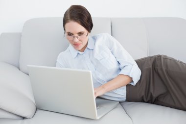 akıllıca giyimli kadın kanepede dizüstü kullanarak