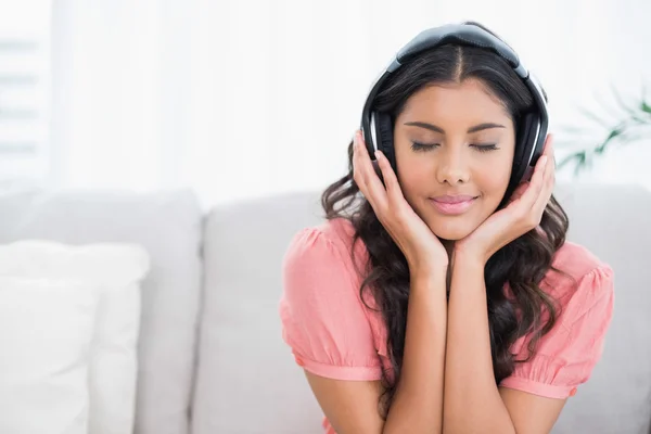 Spokojny, ładny brunetka siedzi na kanapie, słuchając muzyki z clos — Zdjęcie stockowe