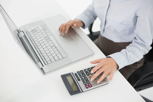 Средняя секция бизнесвумен с помощью ноутбука и калькулятора — стоковое фото