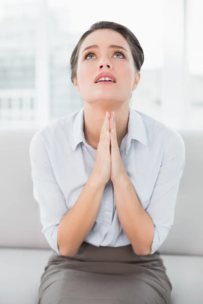 Worried well dressed woman with joined hands looking up — Stock Photo, Image