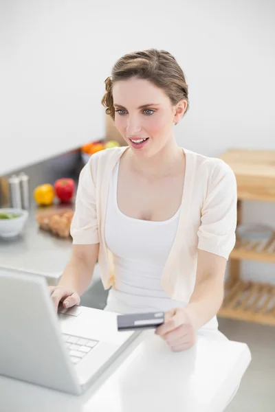 Astonished gorgeous woman using her notebook for home shopping — Stock Photo, Image