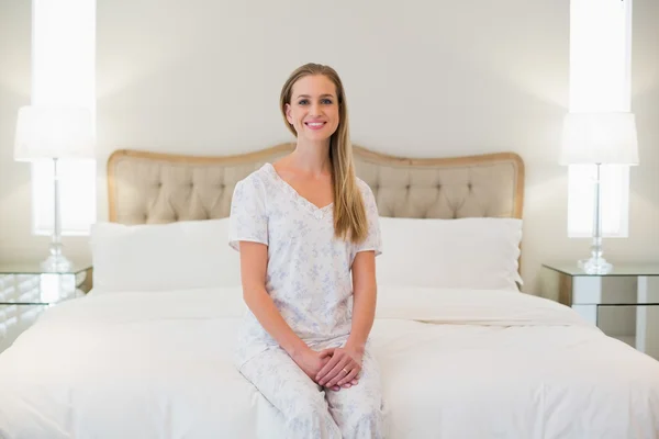 Естественная веселая женщина, сидящая на кровати — стоковое фото