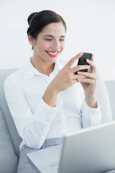 Sonriendo mujer bien vestida usando teléfono celular y portátil — Foto de Stock