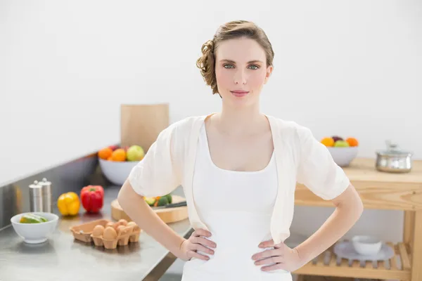 Ernstige brunette vrouw poseren in keuken met handen op de heupen — Stockfoto