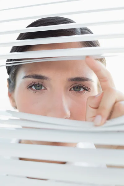 Young business woman peeking through blinds — Stock Photo, Image