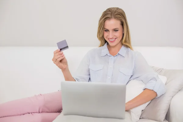 Zufriedene lässige Blondine entspannt auf Couch beim Online-Shopping — Stockfoto