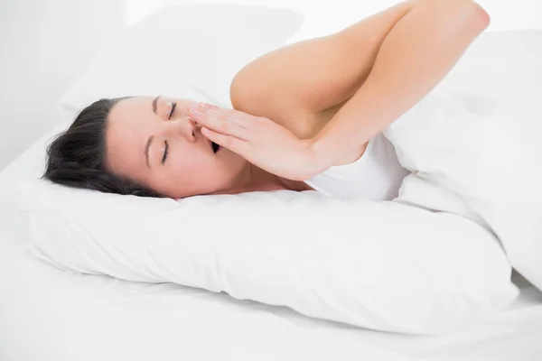 Красивая женщина зевает в постели с закрытыми глазами — стоковое фото