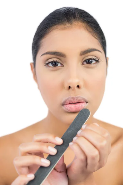 Serious nude brunette using nail file — Stock Photo, Image