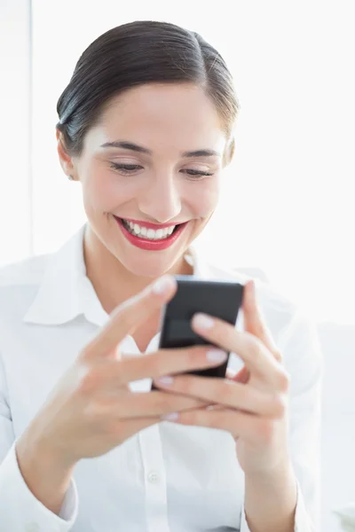 Smiling business woman looking at mobile phone — Stock Photo, Image