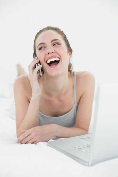 Cheerful casual woman using cellphone and laptop — Stock Photo, Image