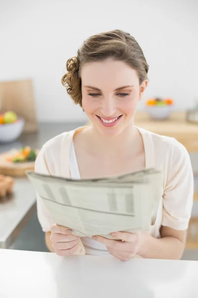 Mujer joven y fresca leyendo el periódico sentado en su cocina — Foto de Stock