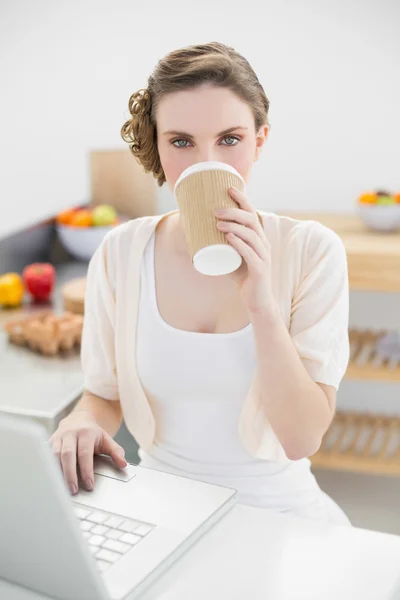 Mooie vrouw drinken van wegwerp beker met behulp van haar notitieblok — Stockfoto