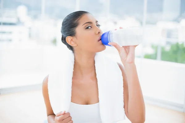 Calm toned brunette with towel drinking from sports bottle — Stock Photo, Image