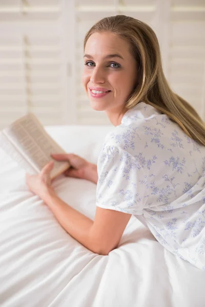 Natural happy woman lying on bed holding book — Stock Photo, Image